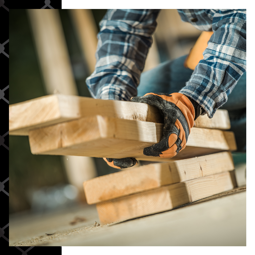 contractor wearing work gloves to pick of a stack of 2x4s